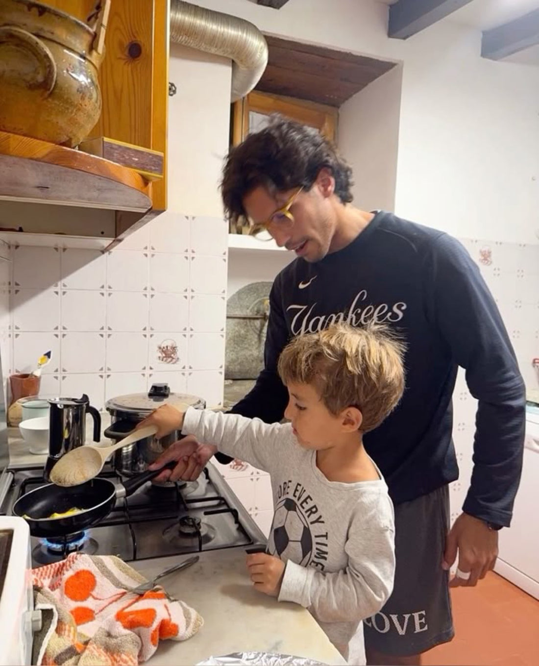 Padre cocinando con su hijo, que prueba el gesto con sus propias manos