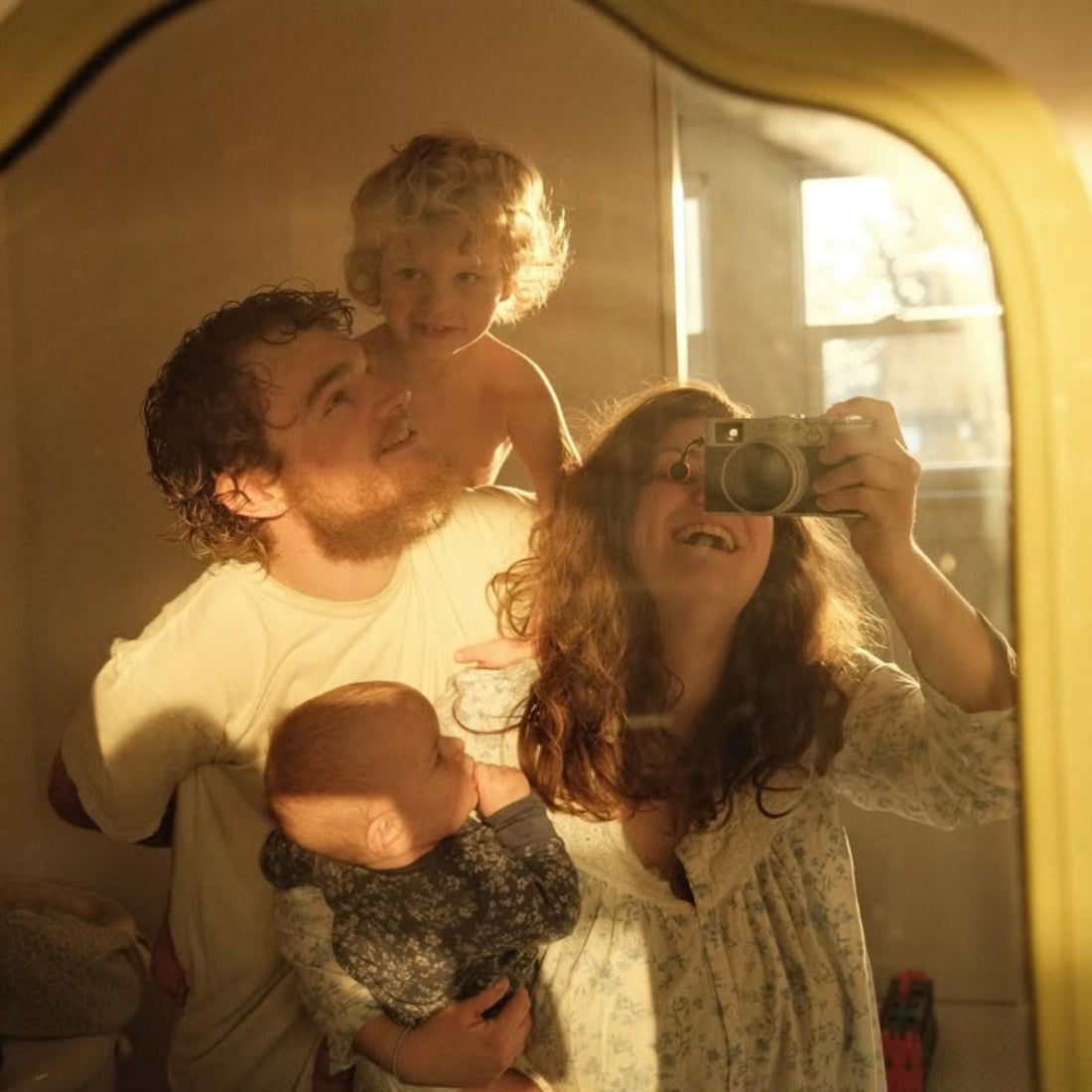 Familia entera reflejada en el espejo de casa con luz de primera hora de la manana, sin ninguna pantalla